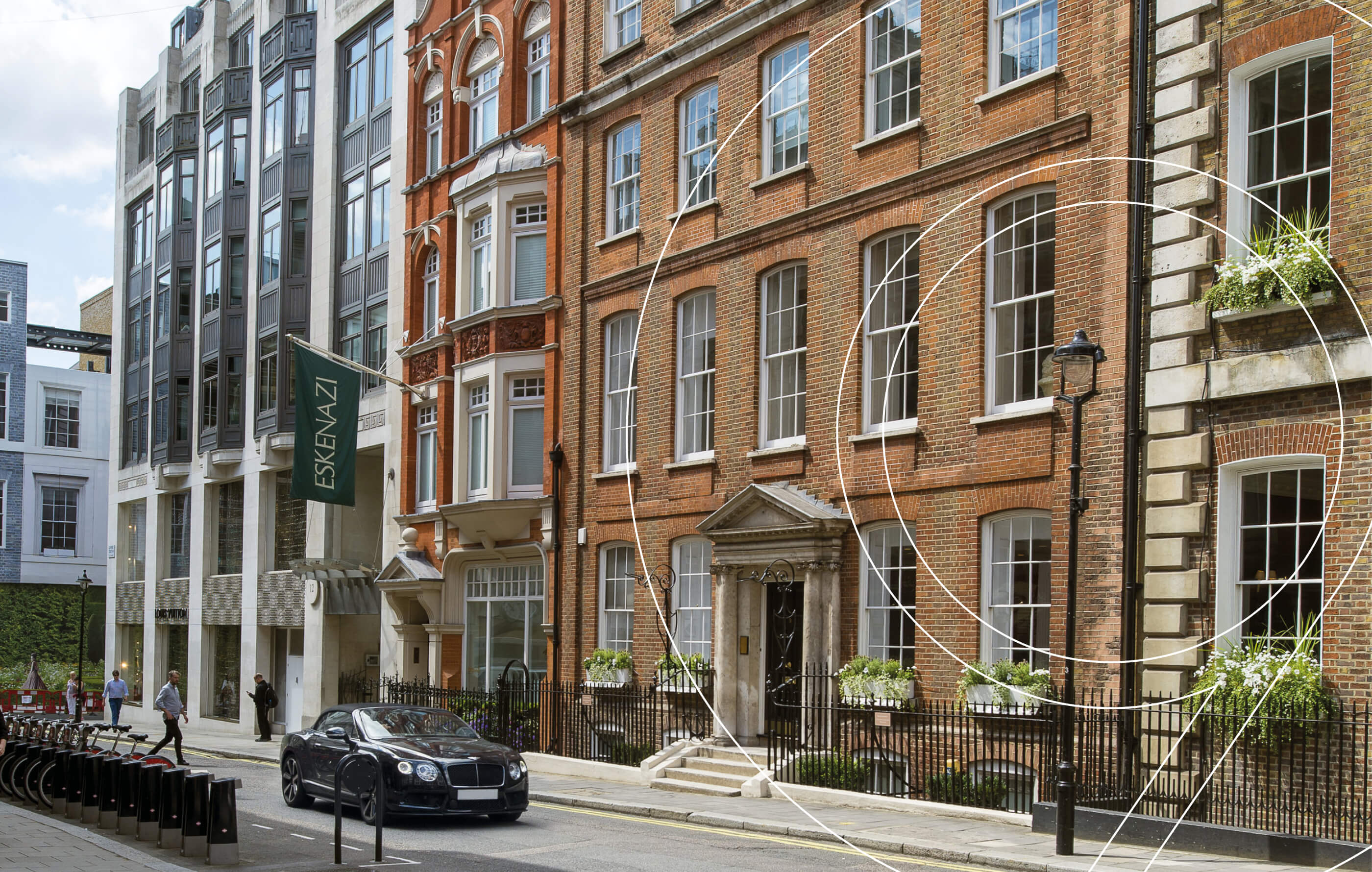 Full screen street view image of the property, with a red brick facade, white sash windows and hanging flower baskets