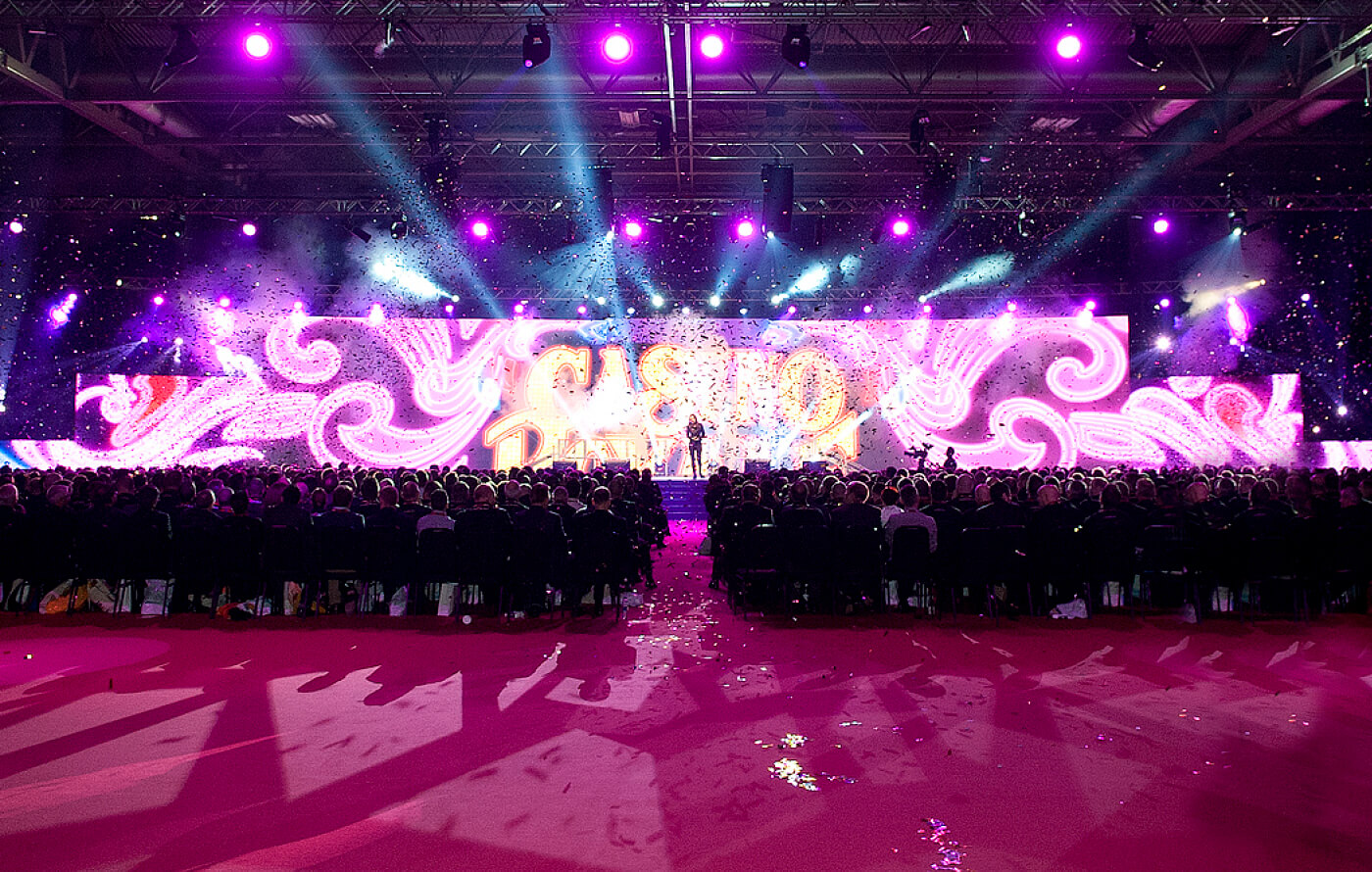 Photo from the event, taken from the back of the room facing the stage, as glitter and coloured confetti fall from the ceiling