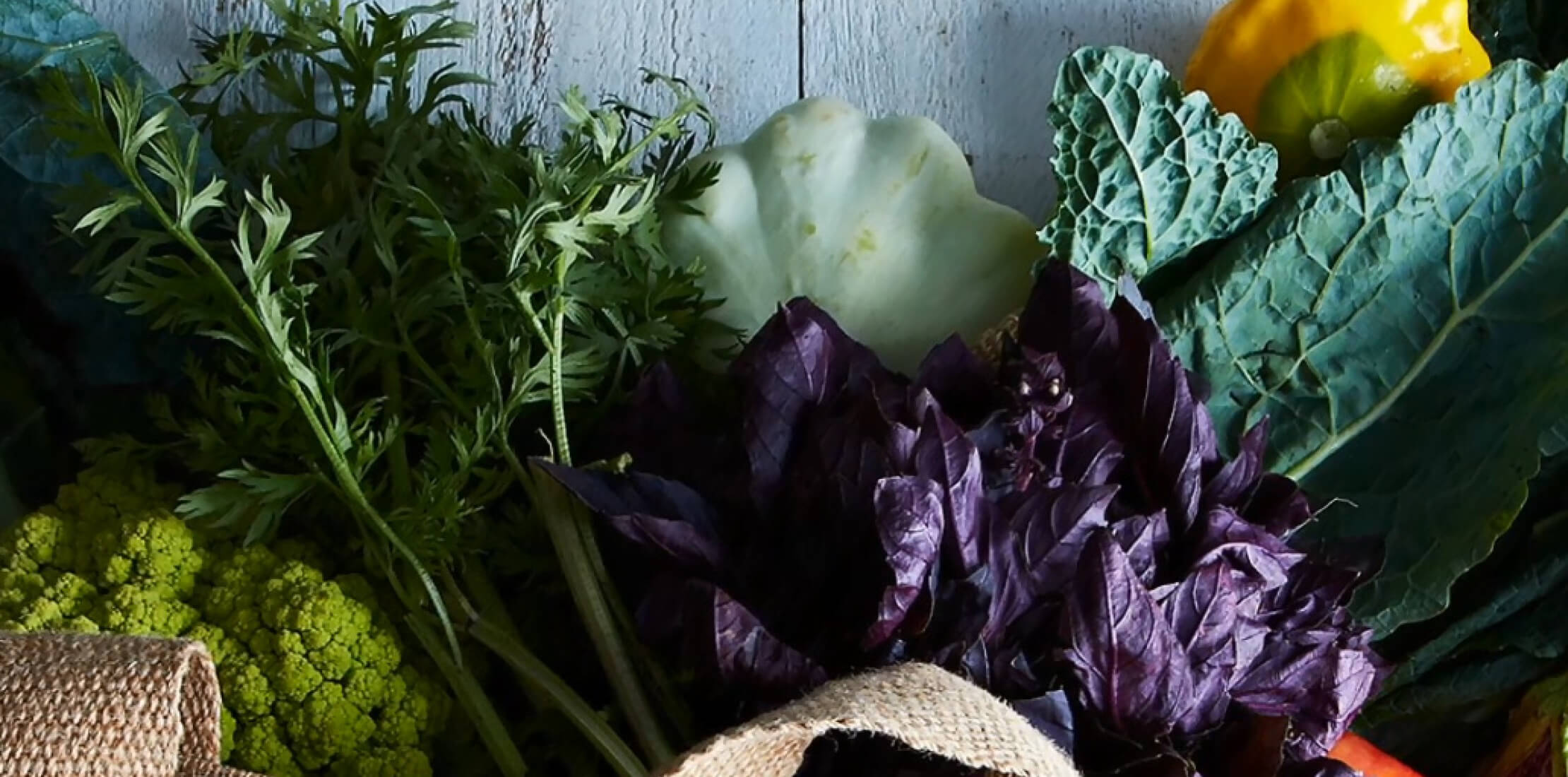 Closely cropped photo of fruit and vegetables on a rustic blue wooden table